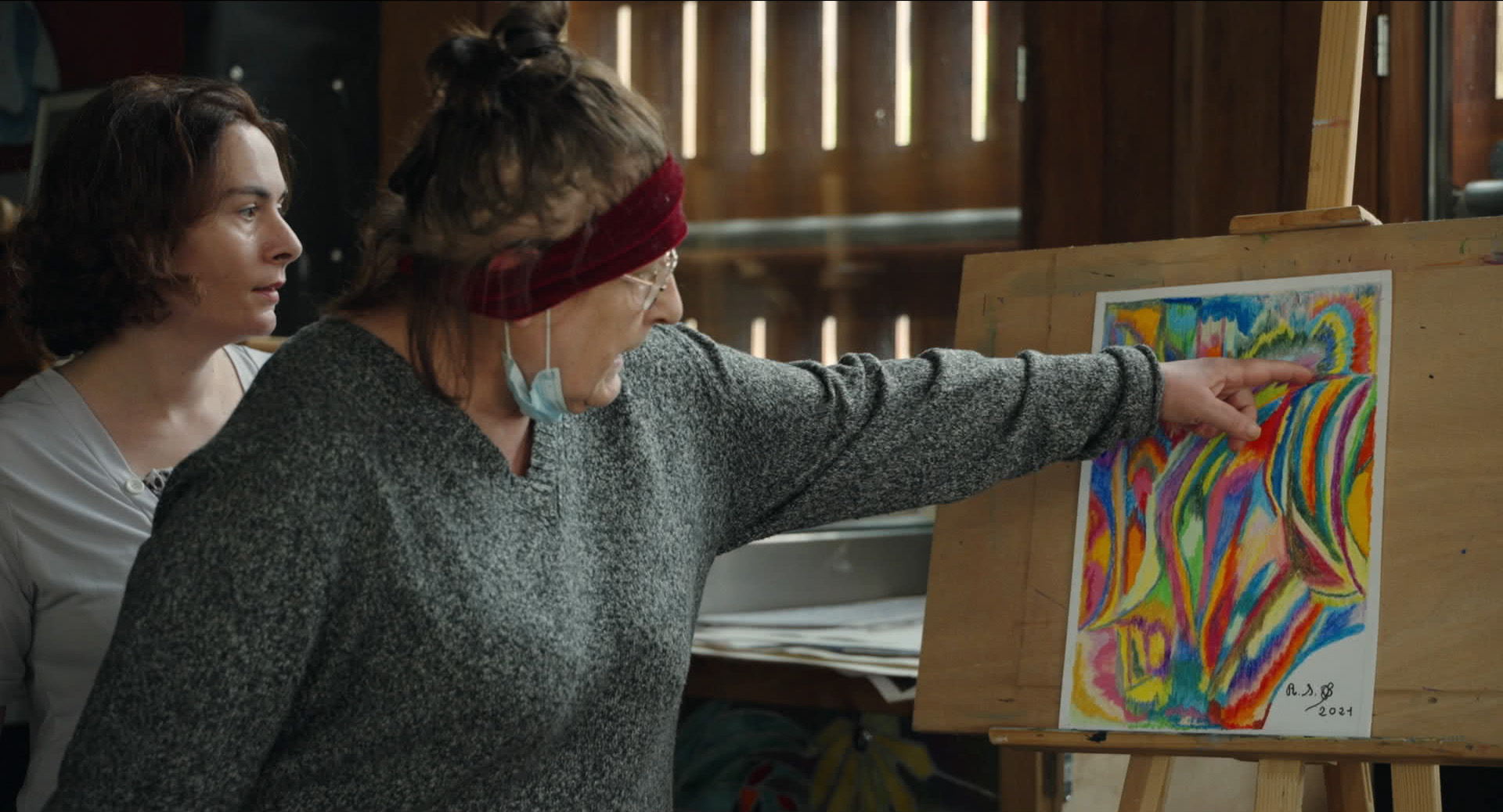 une femme montre une peinture qu'elle est en train de faire