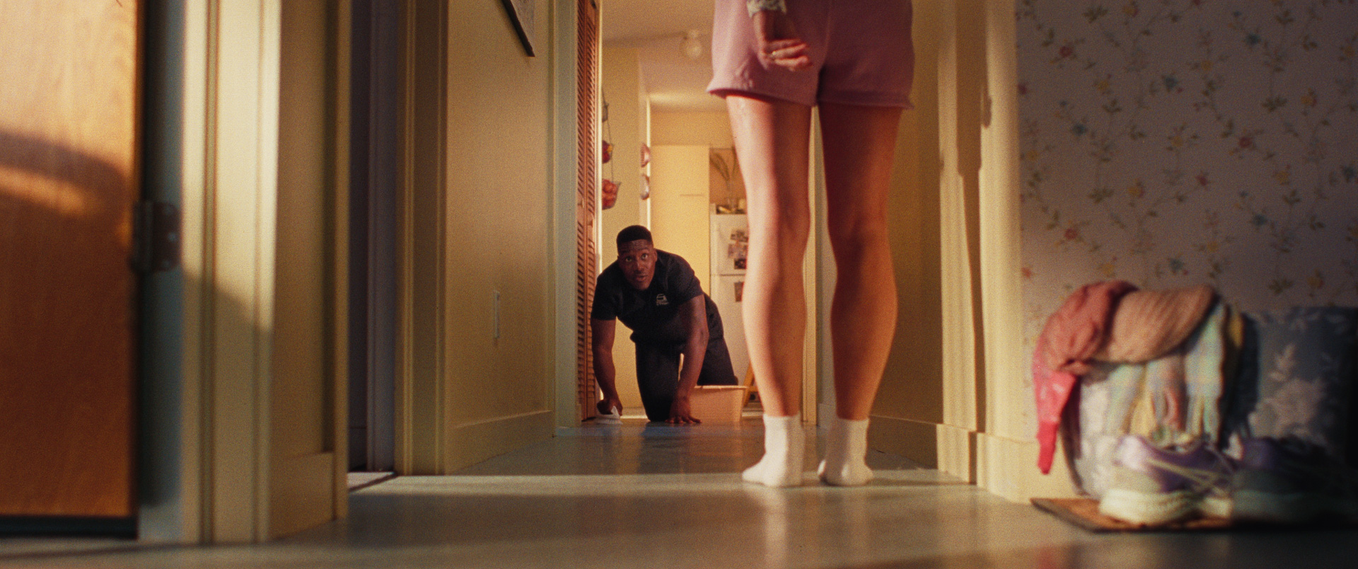 homme à quatre pattes dans un couloir devant jambes nues de femme