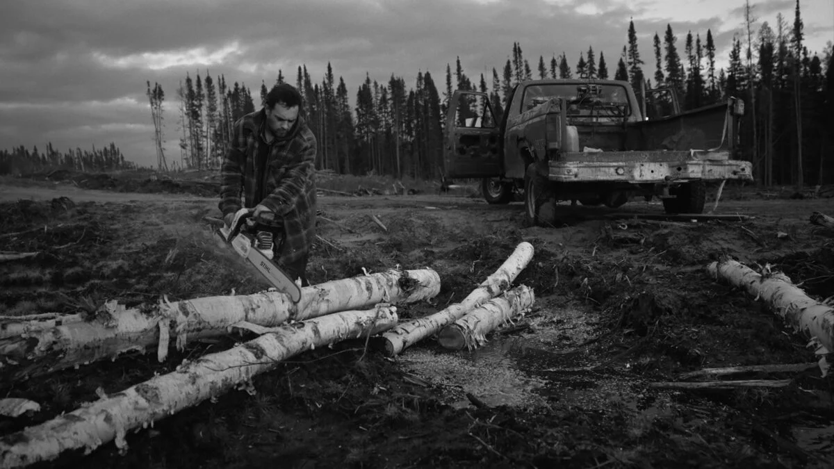 image noir et blanc d'un homme qui coupe un tronc d'arbre